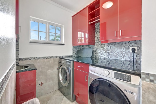 laundry room with ornamental molding, washing machine and clothes dryer, tile walls, light tile patterned floors, and cabinets