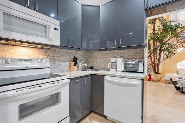 kitchen featuring white appliances, blue cabinets, light stone countertops, and tasteful backsplash