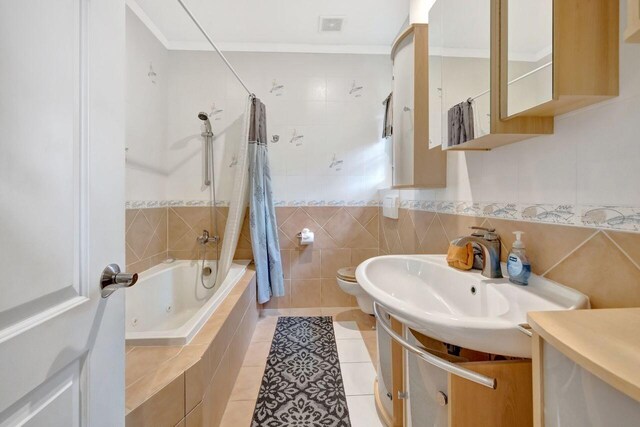 full bathroom featuring tile walls, vanity, shower / bathtub combination with curtain, tile patterned flooring, and ornamental molding