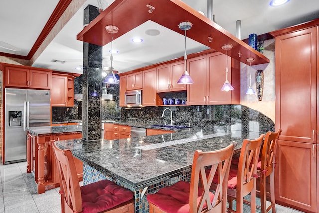 kitchen with a kitchen breakfast bar, stainless steel appliances, decorative light fixtures, sink, and dark stone countertops