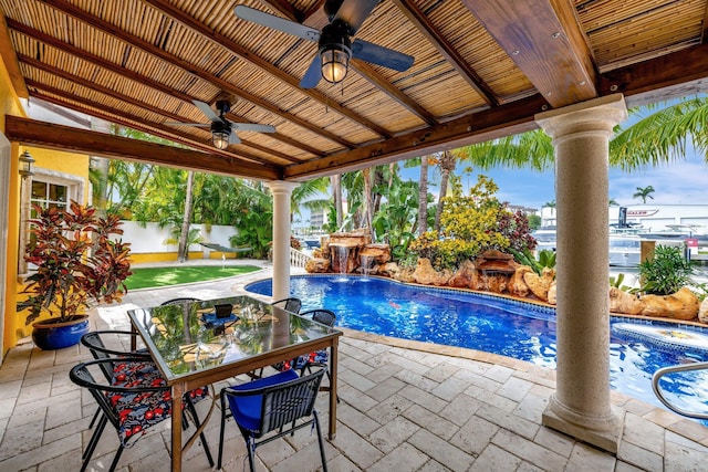 view of swimming pool with a patio area, ceiling fan, an outdoor stone fireplace, and pool water feature