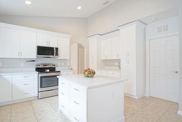 kitchen with stainless steel appliances, white cabinets, a kitchen island, lofted ceiling, and light tile patterned flooring