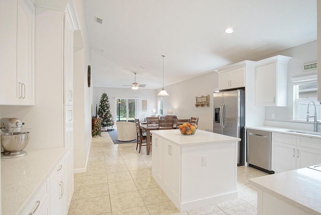 kitchen with ceiling fan, sink, a center island, lofted ceiling, and appliances with stainless steel finishes