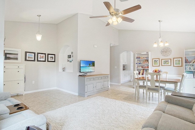 tiled living room with ceiling fan with notable chandelier and high vaulted ceiling