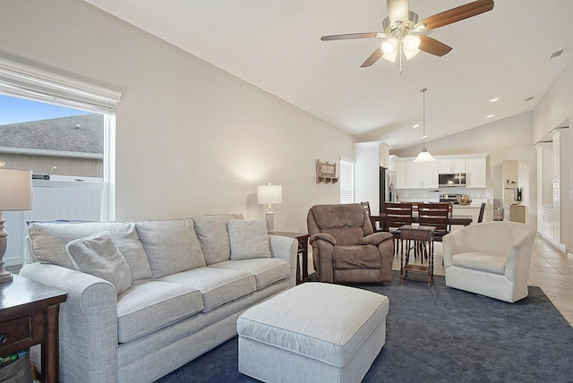 living room featuring vaulted ceiling, dark tile patterned floors, and ceiling fan