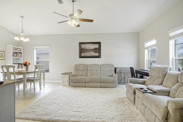 living room with vaulted ceiling, light tile patterned floors, and ceiling fan with notable chandelier