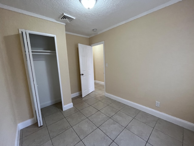 unfurnished bedroom featuring light tile patterned floors, a textured ceiling, a closet, and ornamental molding