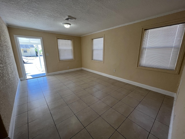 spare room featuring a textured ceiling, light tile patterned floors, and ornamental molding