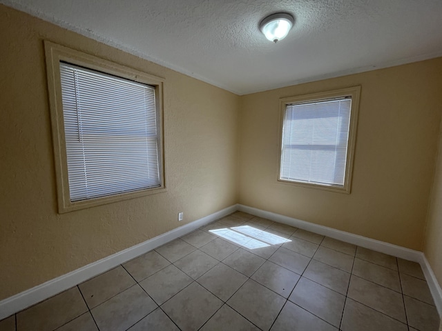 unfurnished room with light tile patterned flooring and a textured ceiling