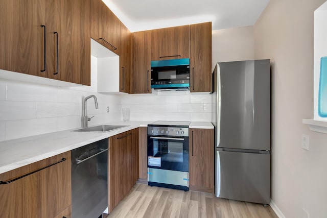 kitchen with light hardwood / wood-style floors, sink, backsplash, and black appliances