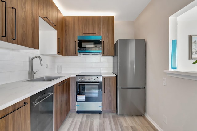 kitchen featuring sink, backsplash, black appliances, and light hardwood / wood-style flooring