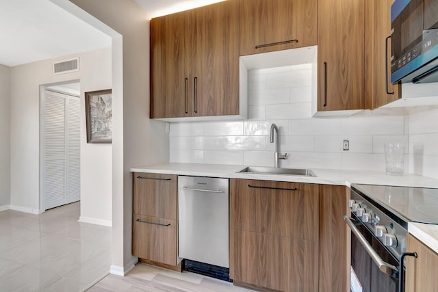 kitchen with sink, backsplash, and appliances with stainless steel finishes