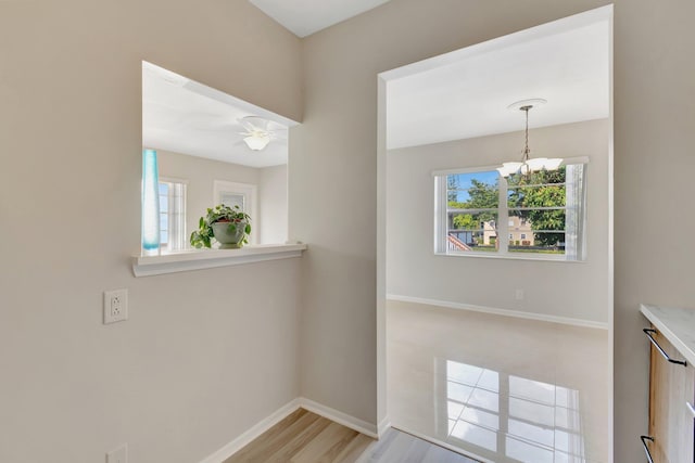 unfurnished dining area with ceiling fan with notable chandelier and light hardwood / wood-style floors