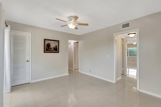 tiled empty room featuring ceiling fan