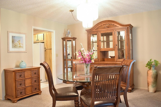 dining room featuring a textured ceiling, light colored carpet, and an inviting chandelier