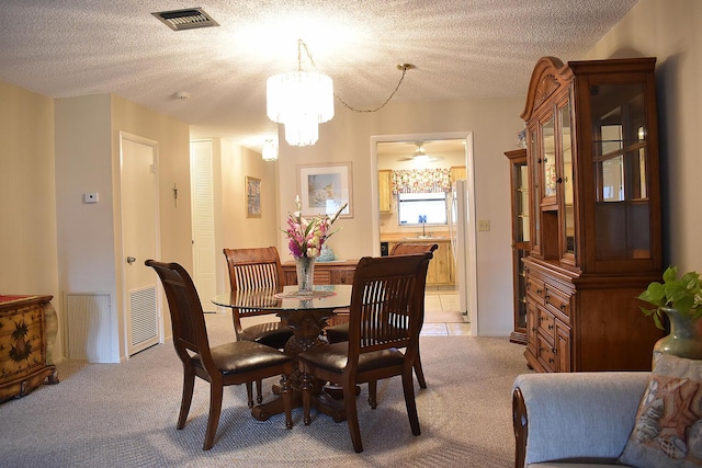 carpeted dining space featuring sink, a chandelier, and a textured ceiling