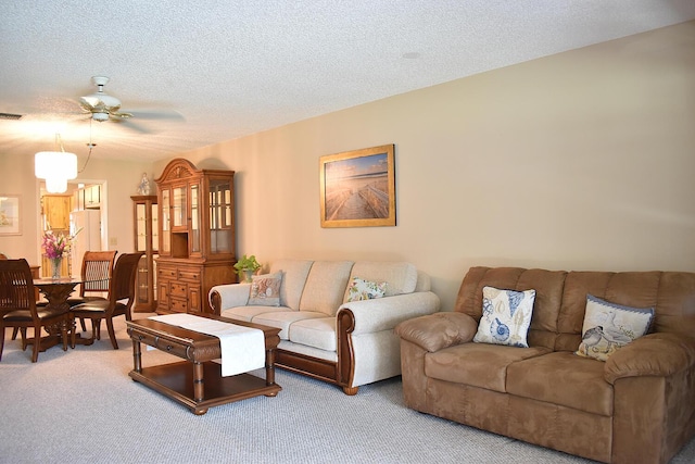 living room with carpet flooring, ceiling fan, and a textured ceiling