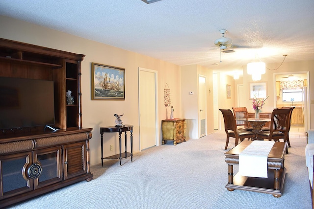 carpeted living room featuring a textured ceiling and ceiling fan