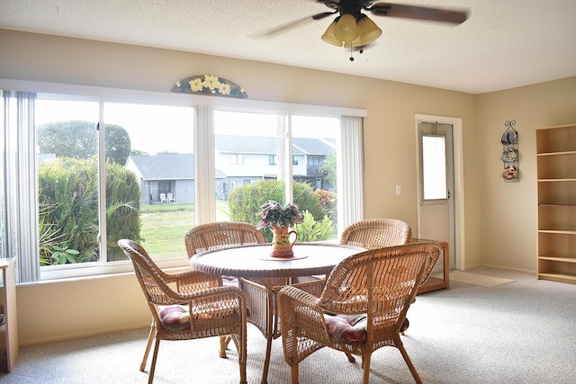 carpeted dining space featuring ceiling fan and a textured ceiling