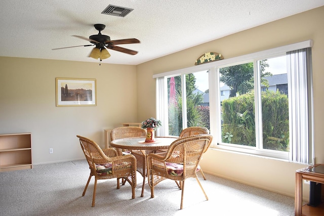 carpeted dining room featuring ceiling fan, a healthy amount of sunlight, and a textured ceiling