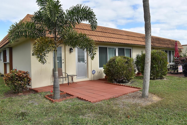 back of property featuring a patio area and a lawn