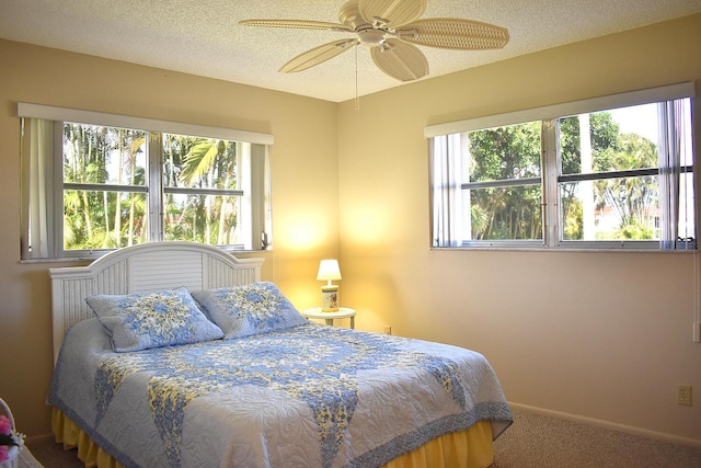 bedroom with multiple windows, ceiling fan, carpet floors, and a textured ceiling