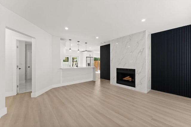 unfurnished living room with a high end fireplace, french doors, and light hardwood / wood-style flooring