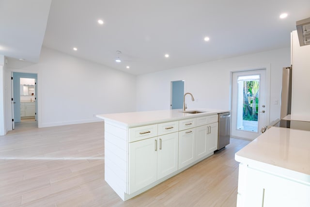 kitchen featuring stove, a kitchen island with sink, sink, stainless steel dishwasher, and white cabinetry