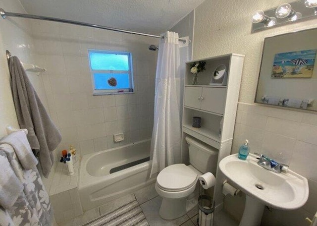 full bathroom with sink, tile patterned flooring, toilet, shower / bathtub combination with curtain, and a textured ceiling