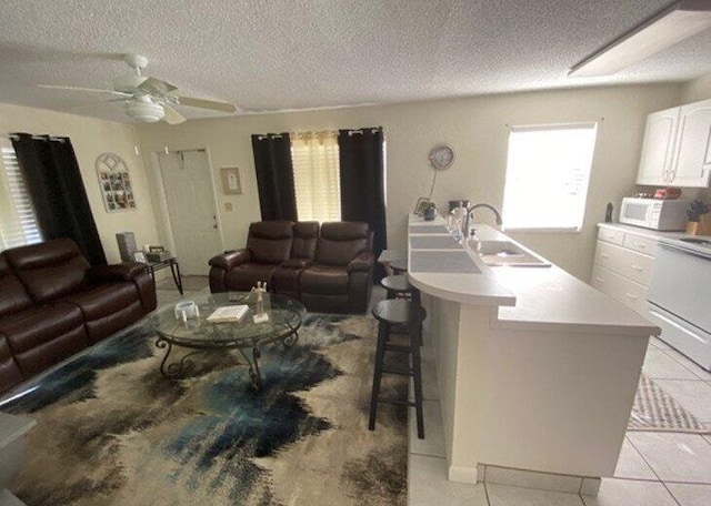 tiled living room featuring ceiling fan, sink, and a textured ceiling