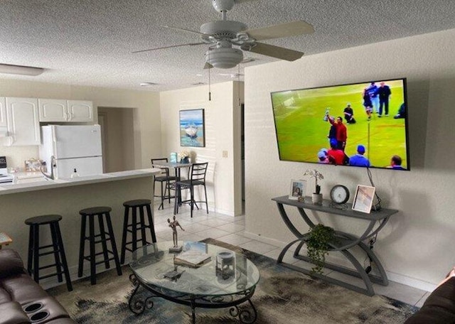 living room with light tile patterned floors, a textured ceiling, and ceiling fan