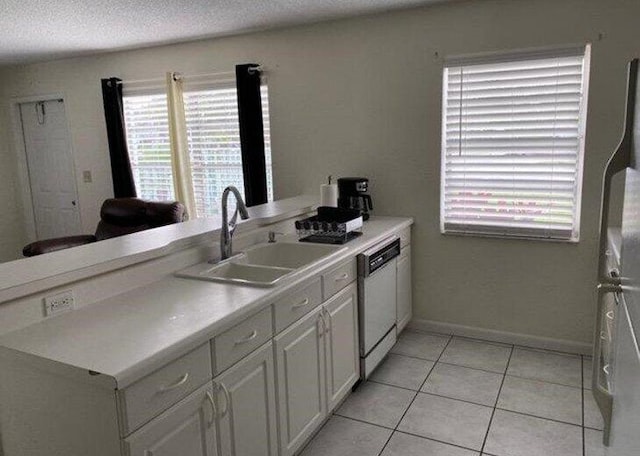 kitchen featuring a textured ceiling, white dishwasher, sink, white cabinetry, and light tile patterned flooring