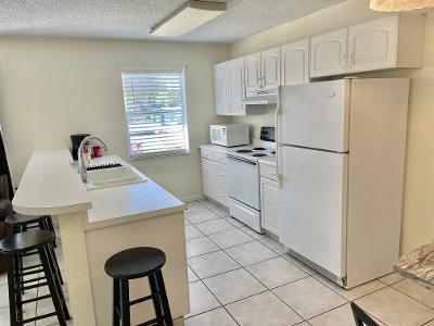 kitchen with white cabinetry, sink, kitchen peninsula, white appliances, and a breakfast bar area