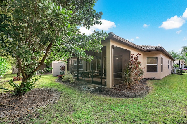 back of house with a sunroom and a lawn