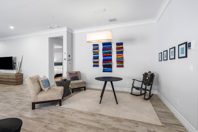 sitting room with a textured ceiling, light wood-type flooring, and crown molding