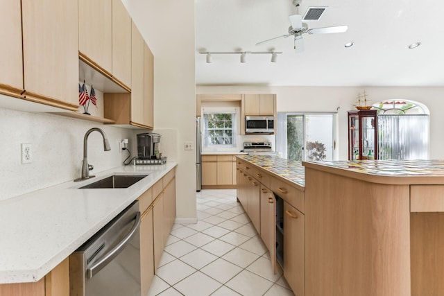 kitchen featuring light tile patterned flooring, sink, ceiling fan, appliances with stainless steel finishes, and a kitchen island