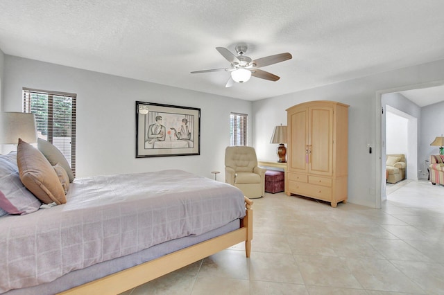 bedroom with ceiling fan, light tile patterned floors, and a textured ceiling