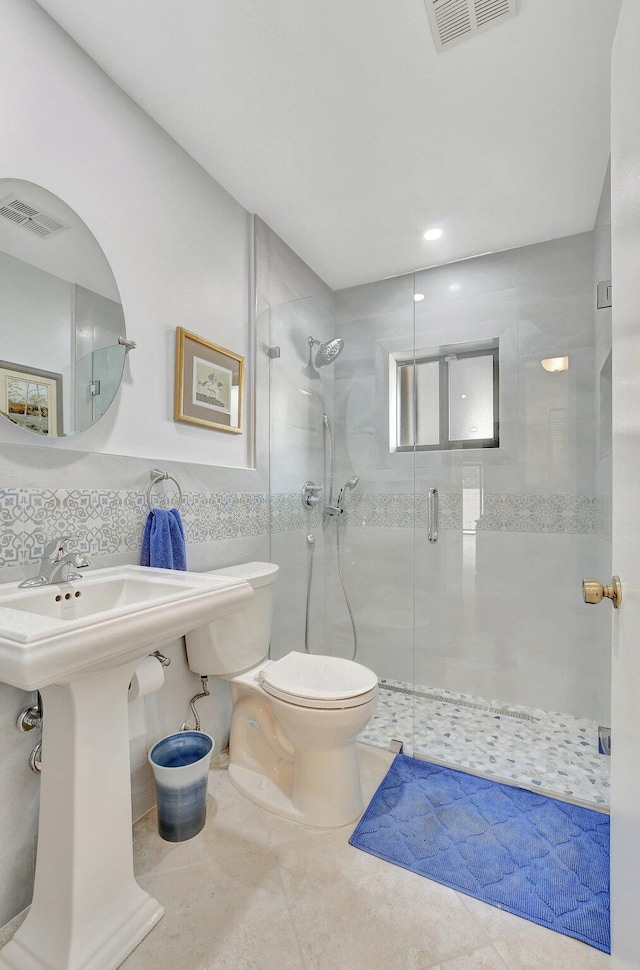 bathroom featuring backsplash, tile patterned flooring, toilet, walk in shower, and tile walls