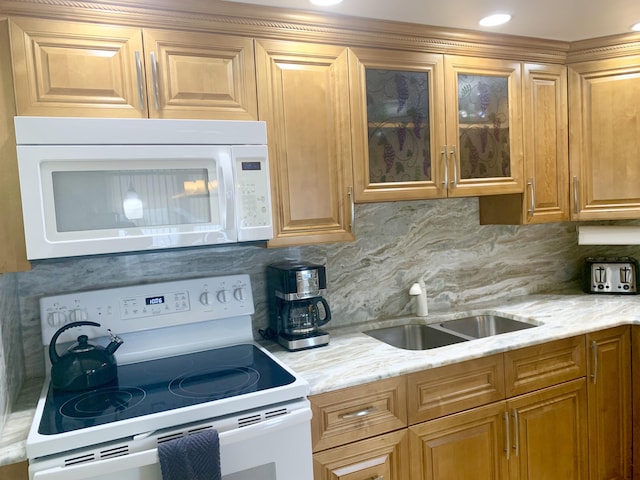 kitchen with light stone countertops, white appliances, sink, and tasteful backsplash