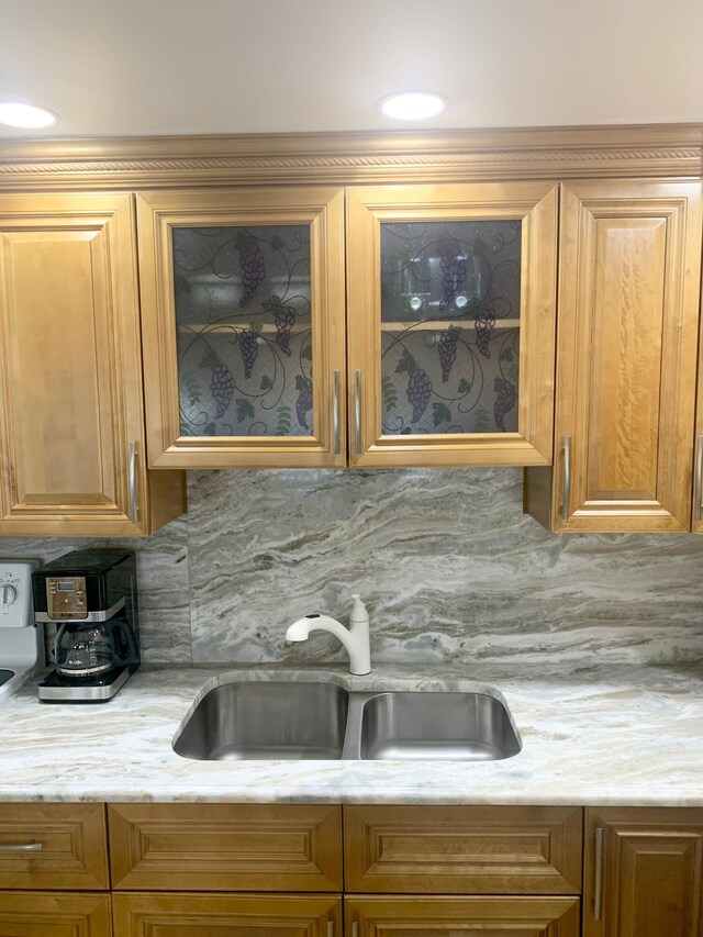 kitchen with tasteful backsplash, light stone countertops, and sink