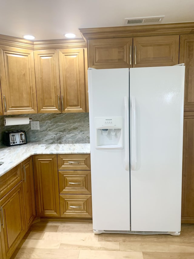 kitchen with backsplash, light stone counters, white refrigerator with ice dispenser, and light wood-type flooring