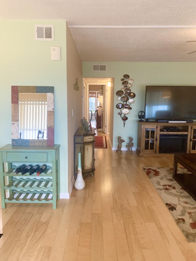 corridor with a healthy amount of sunlight, a textured ceiling, and hardwood / wood-style flooring