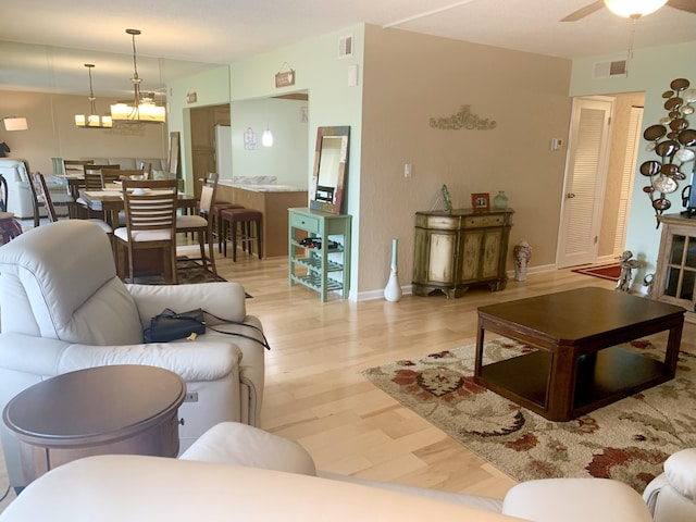 living room featuring light hardwood / wood-style floors and ceiling fan with notable chandelier