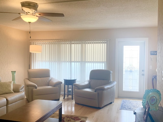 living room featuring ceiling fan, a healthy amount of sunlight, light wood-type flooring, and a textured ceiling