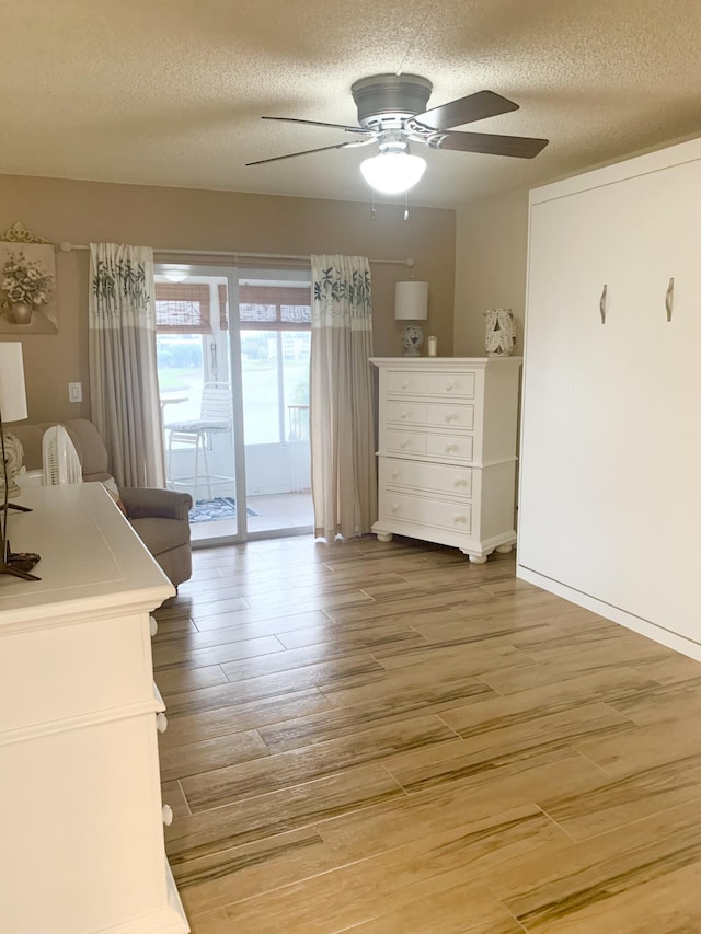 unfurnished bedroom with hardwood / wood-style flooring, ceiling fan, a textured ceiling, and access to outside