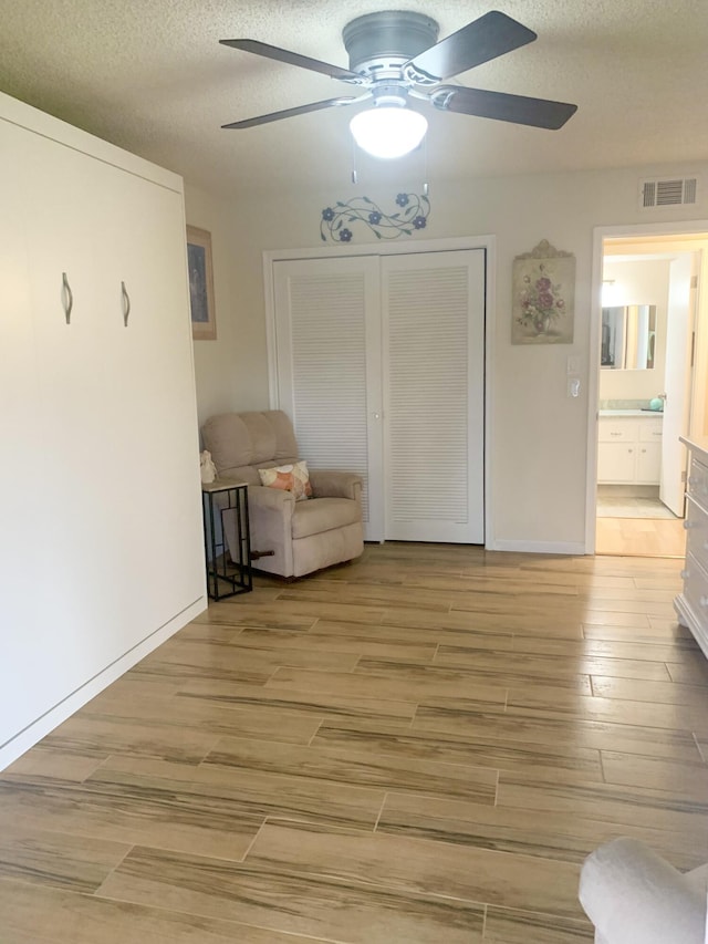 unfurnished room with a textured ceiling, light hardwood / wood-style flooring, and ceiling fan