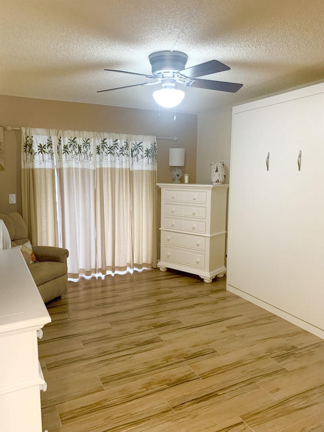 unfurnished bedroom featuring ceiling fan, wood-type flooring, and a textured ceiling