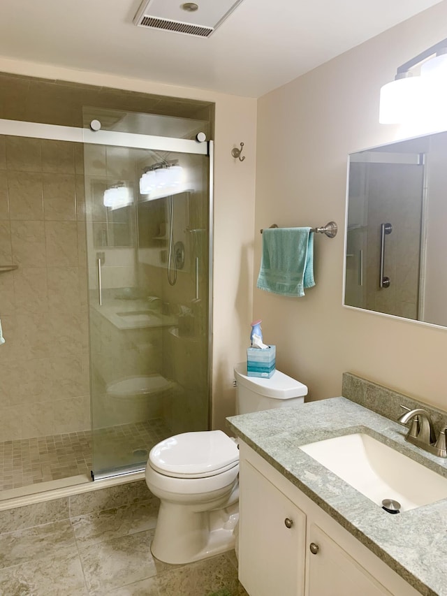 bathroom featuring tile patterned floors, vanity, toilet, and an enclosed shower