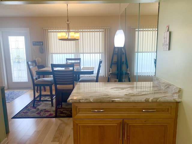 kitchen featuring decorative light fixtures, light hardwood / wood-style floors, and light stone counters