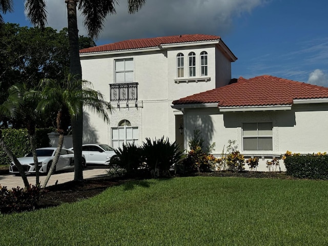 back of property featuring stucco siding, a lawn, and a tile roof